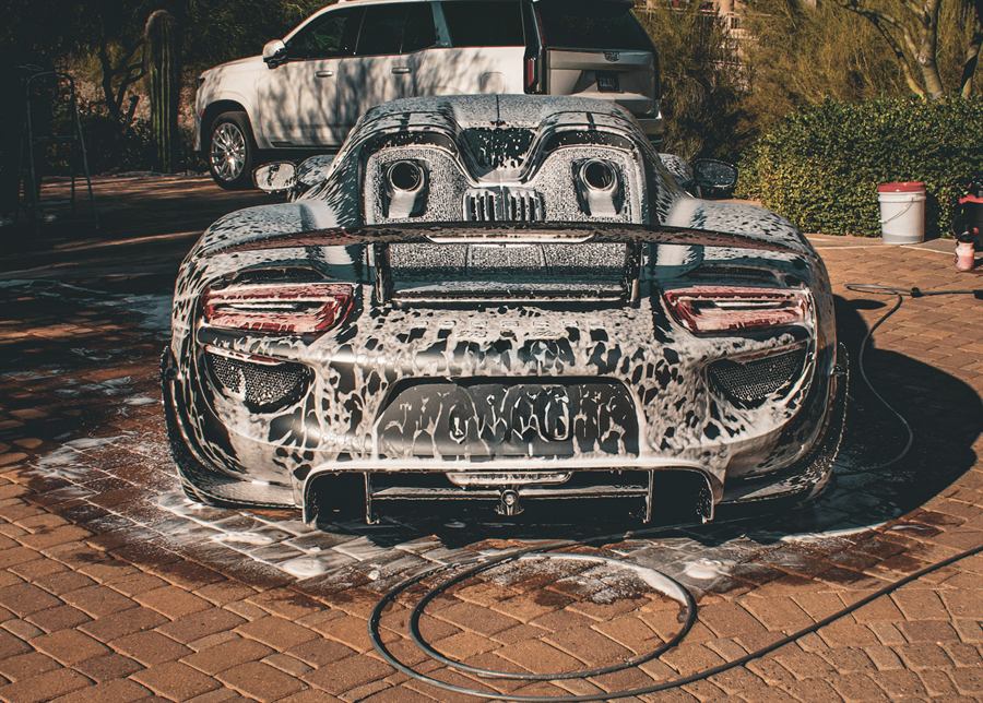 Rear of a Porsche 918 Spyder covered in foam on a paver driveway