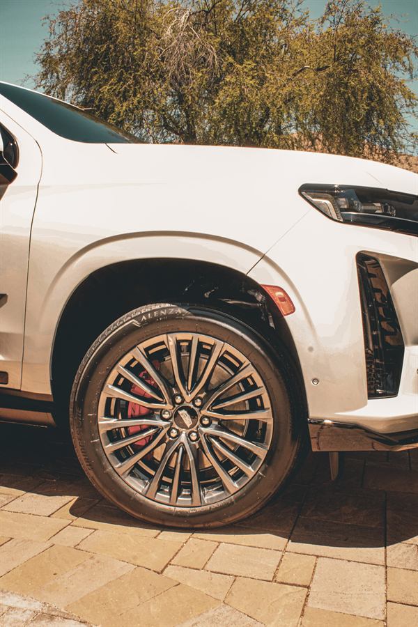 Polished wheel and red brake caliper on a white Cadillac Escalade-V