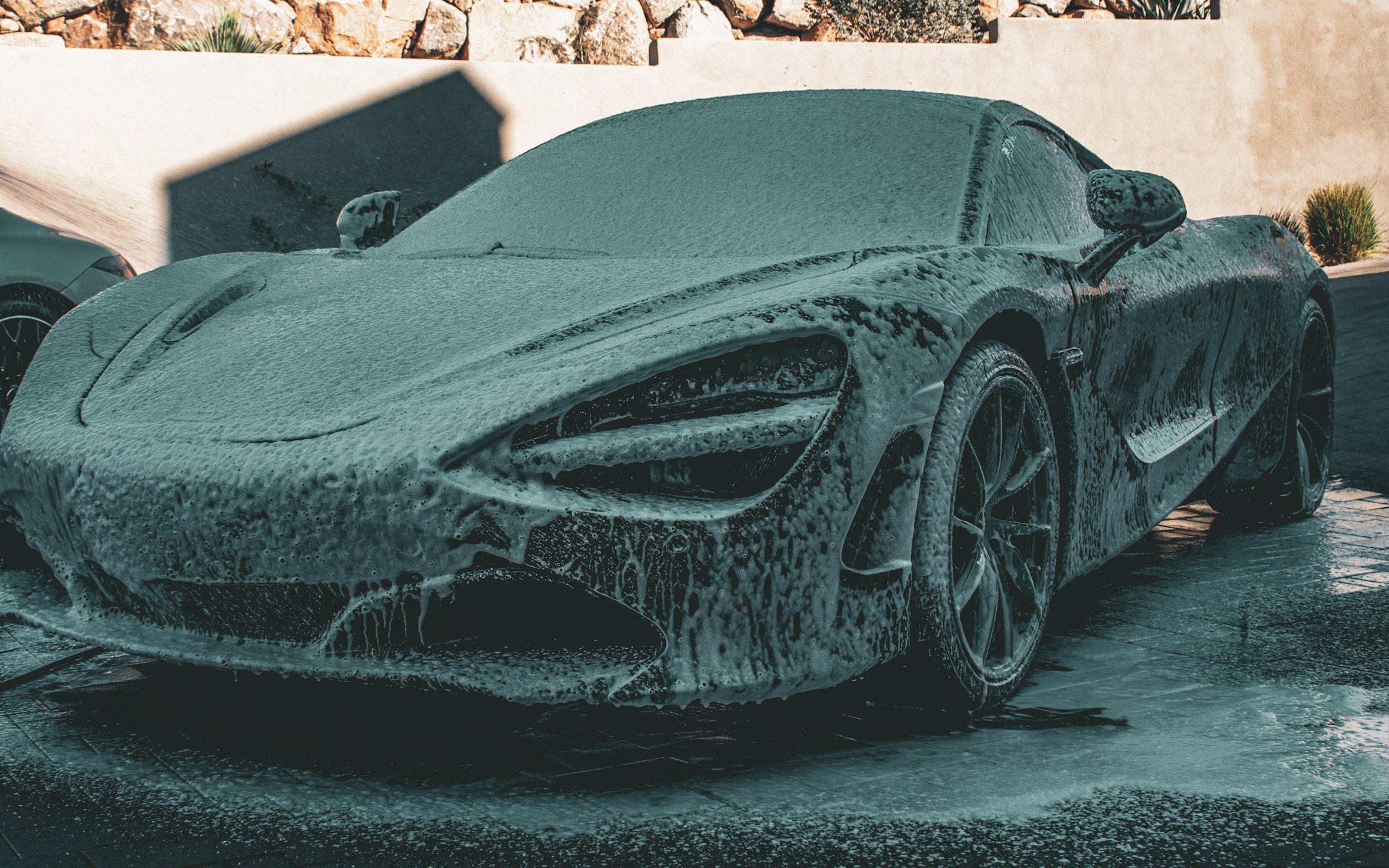 A McLaren 720S buried in thick white foam during a decontamination soak