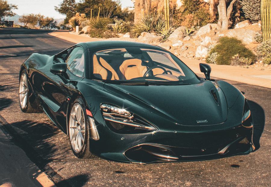 Dark green McLaren 720S parked on a desert road among saguaro cactus at golden hour